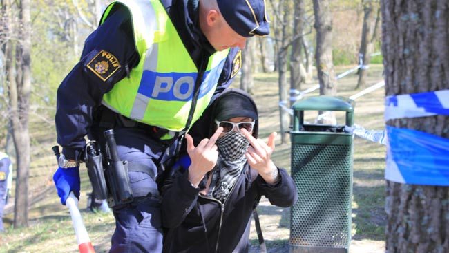 Maskerad kille blir av med vuvuzela som polisen håller i handen och får en tilrättavisning - Foto: Nyheter Idag